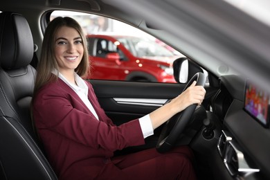 Young woman inside new car in salon