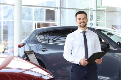 Happy salesman near new red car in salon