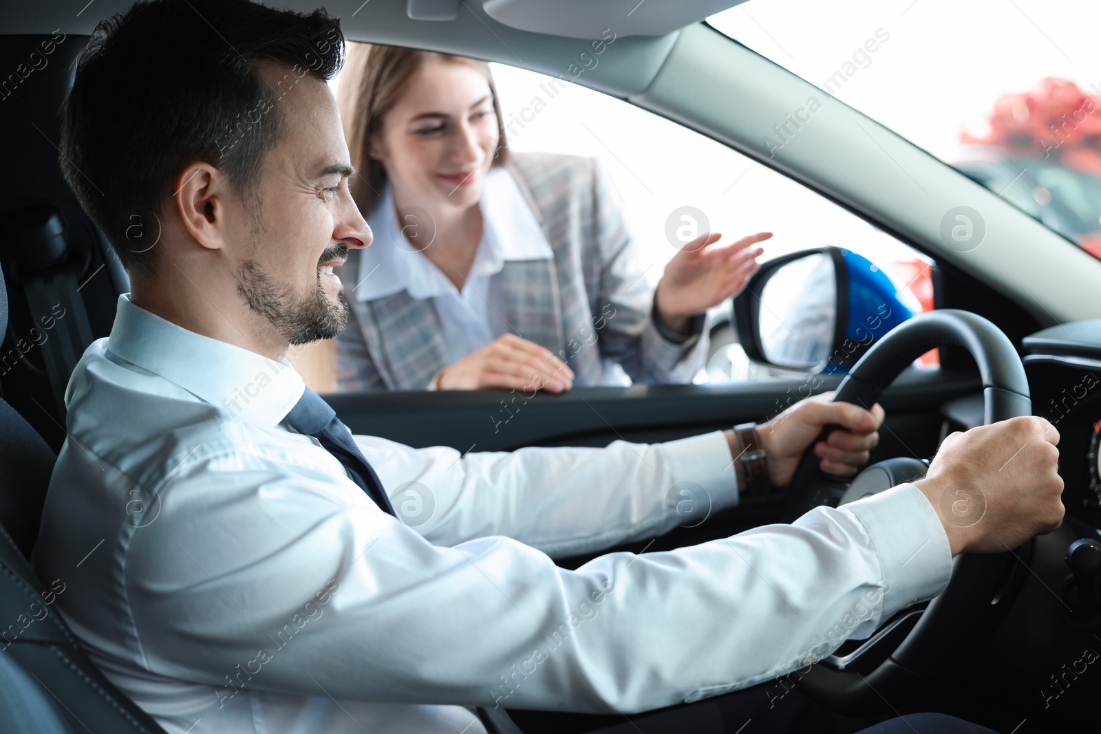 Photo of Saleswoman showing car to client in salon