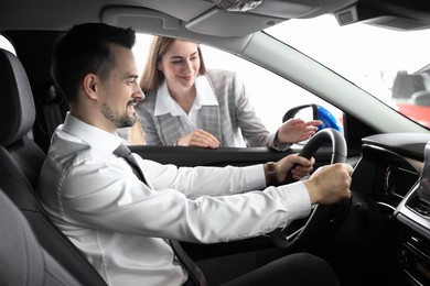 Photo of Saleswoman showing car to client in salon