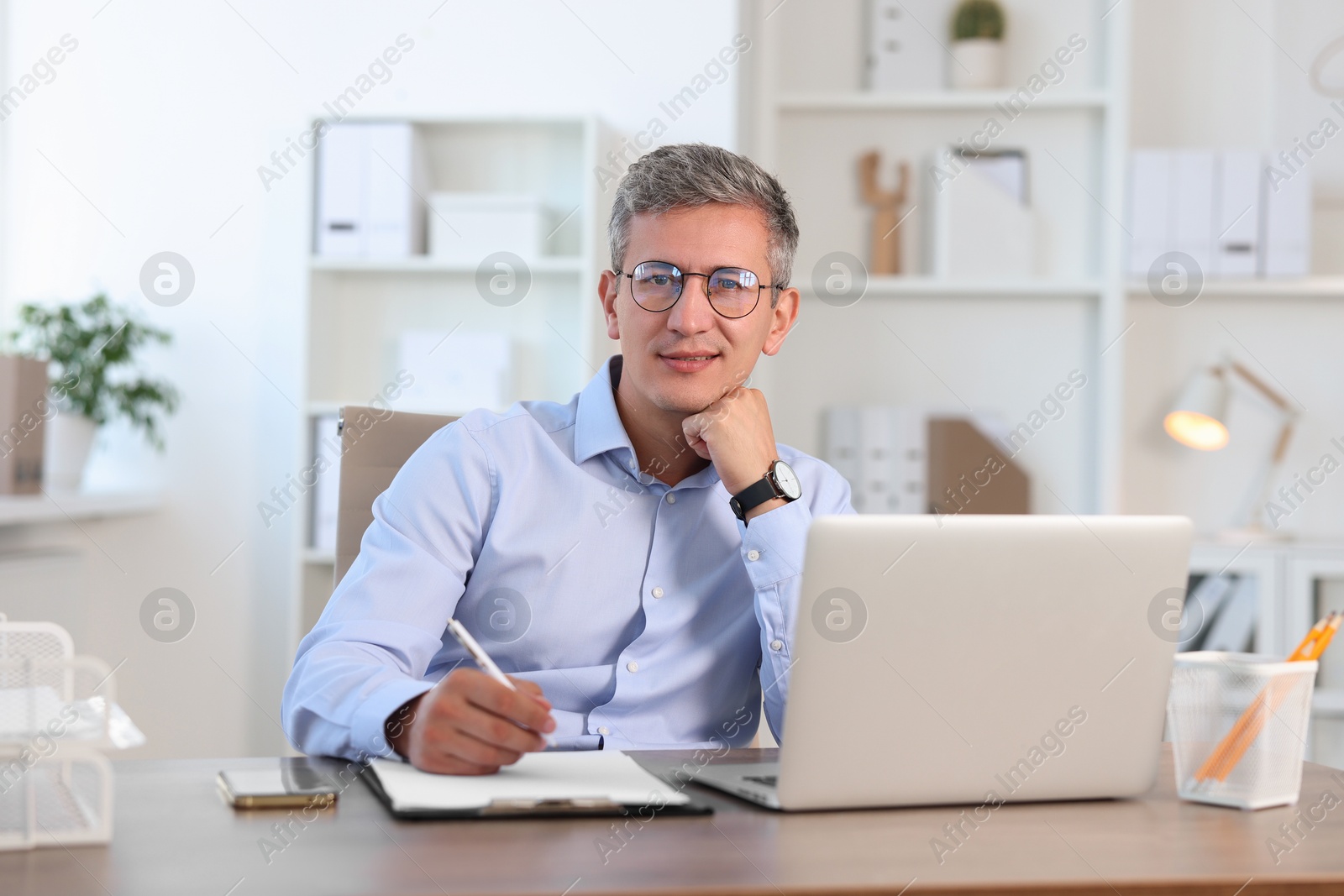 Photo of Portrait of smiling middle aged man at table in office