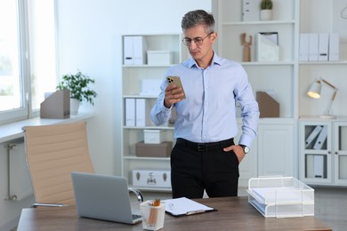 Photo of Middle aged man using smartphone in office