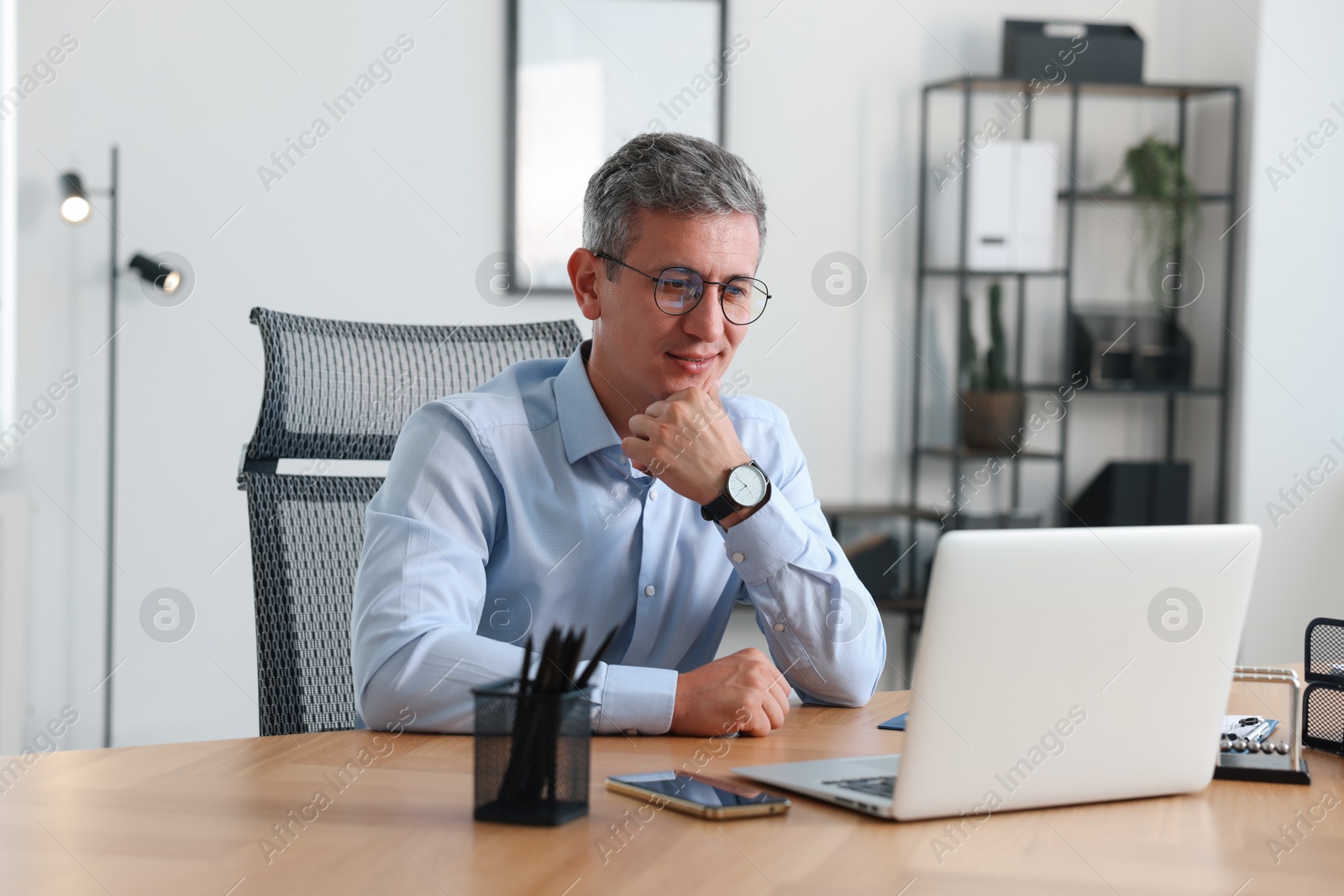 Photo of Middle aged man working with laptop at table in office