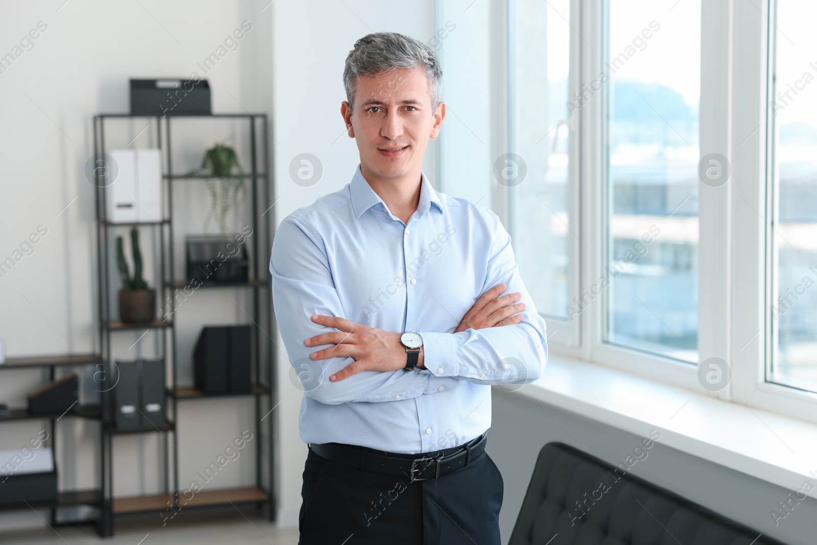 Photo of Portrait of smiling middle aged man with crossed arms in office