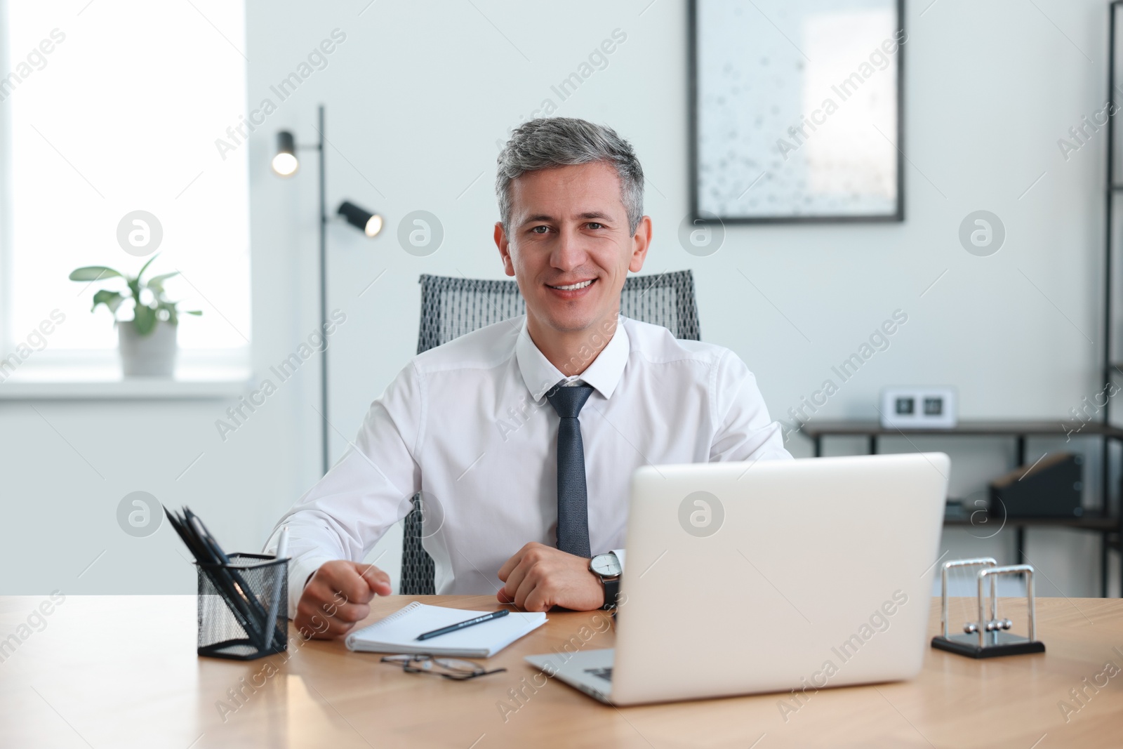 Photo of Portrait of smiling middle aged man at table in office