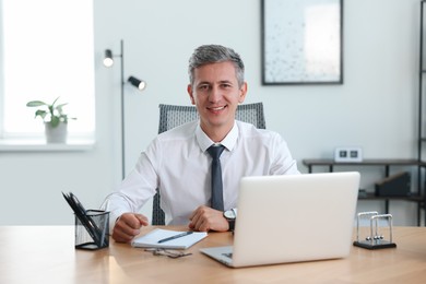 Photo of Portrait of smiling middle aged man at table in office