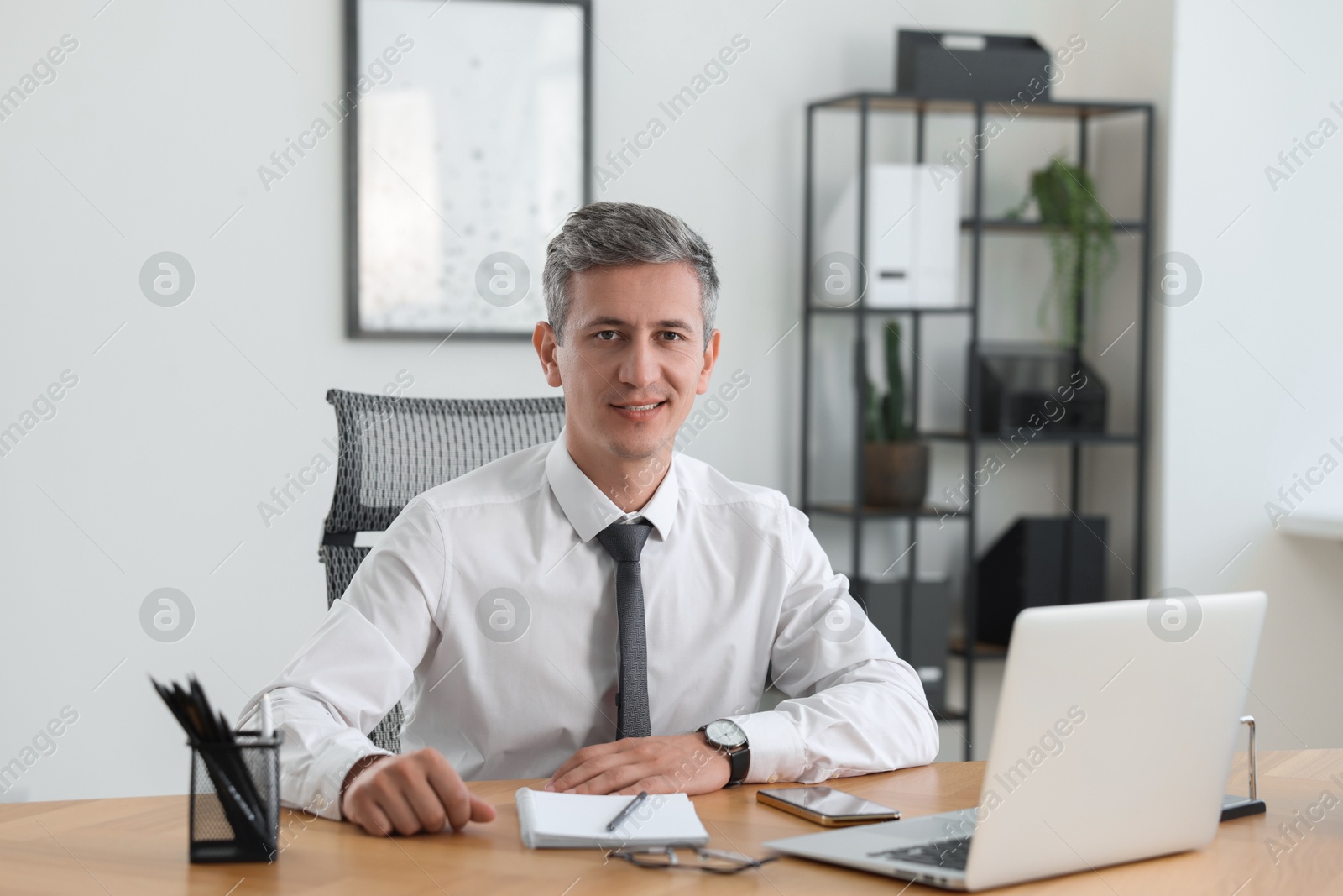 Photo of Portrait of smiling middle aged man at table in office