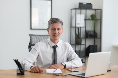 Photo of Portrait of smiling middle aged man at table in office