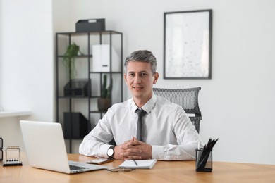 Photo of Portrait of smiling middle aged man at table in office