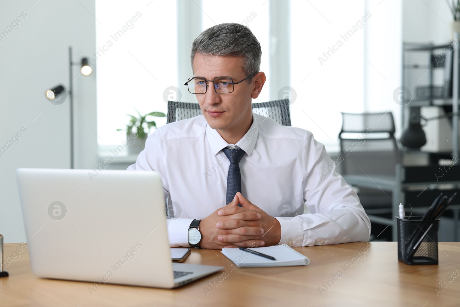 Photo of Middle aged man working with laptop at table in office