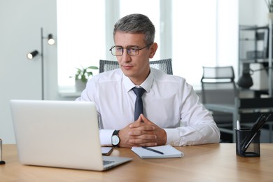 Middle aged man working with laptop at table in office