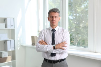 Portrait of middle aged man with crossed arms in office