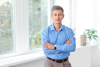 Portrait of middle aged man with crossed arms in office