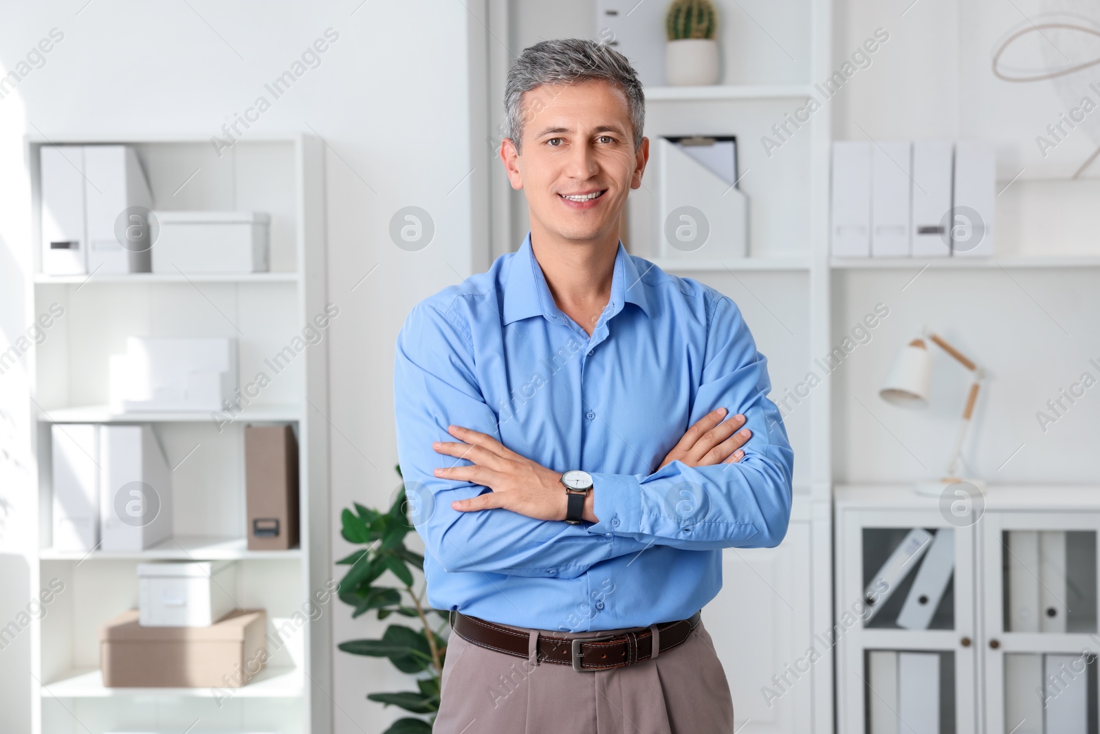 Photo of Portrait of smiling middle aged man with crossed arms in office