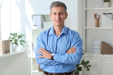 Photo of Portrait of smiling middle aged man with crossed arms in office