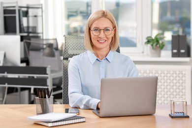 Portrait of smiling middle aged woman at table in office