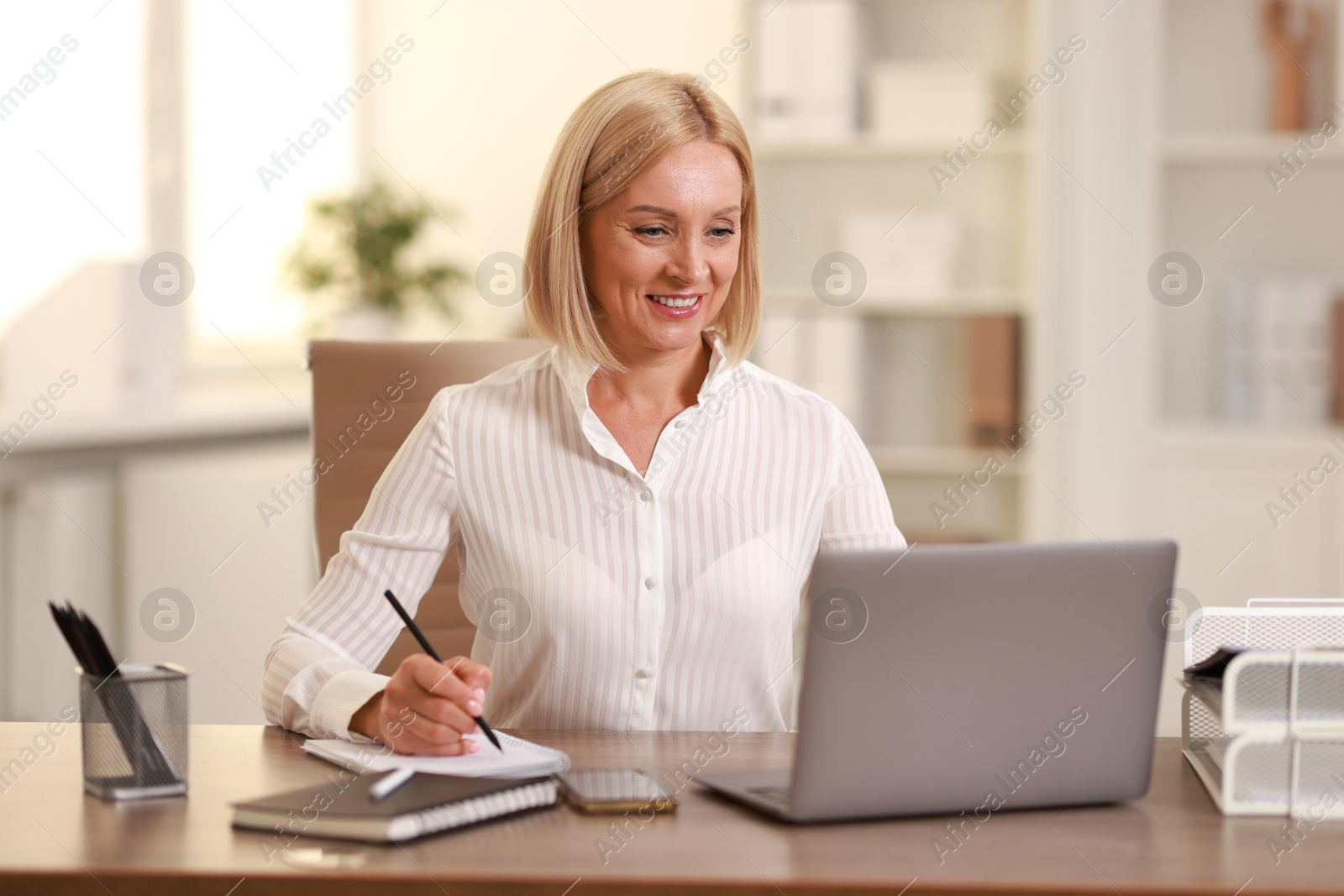 Photo of Smiling middle aged woman working at table in office