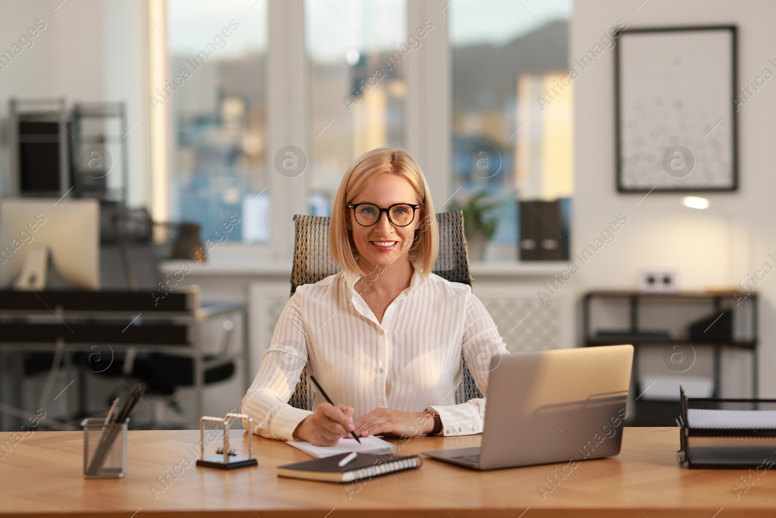 Photo of Portrait of smiling middle aged woman at table in office