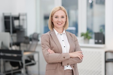 Photo of Portrait of smiling middle aged woman with crossed arms in office