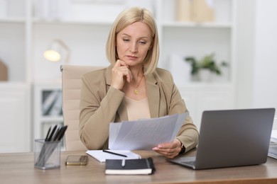 Photo of Middle aged woman working at table in office