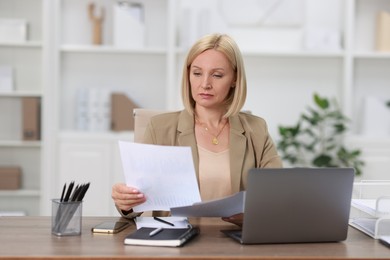 Photo of Middle aged woman working at table in office