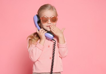 Photo of Cute little girl with handset of telephone on pink background