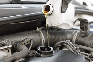 Photo of Man pouring motor oil into car engine, closeup