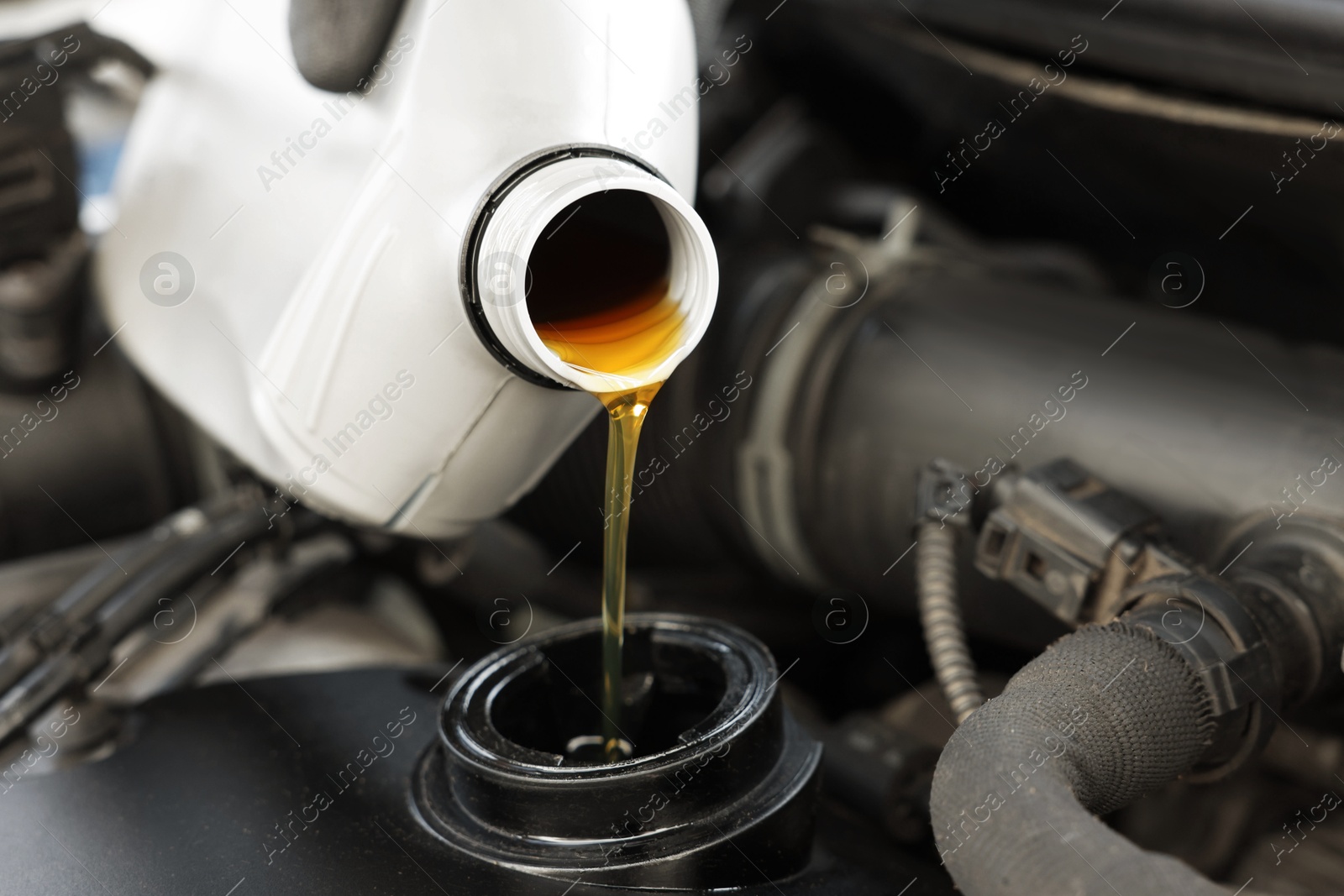 Photo of Man pouring motor oil into car engine, closeup