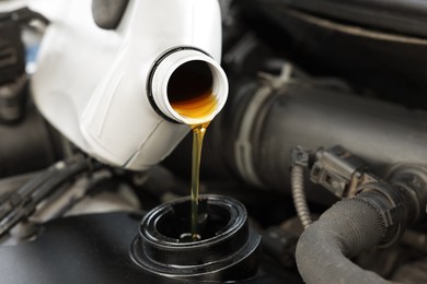 Photo of Man pouring motor oil into car engine, closeup