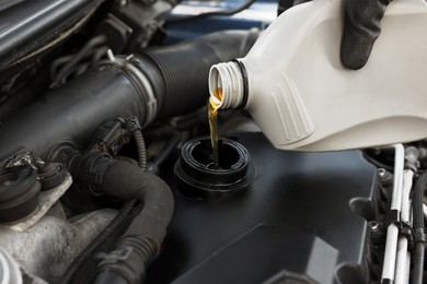 Photo of Man pouring motor oil into car engine, closeup