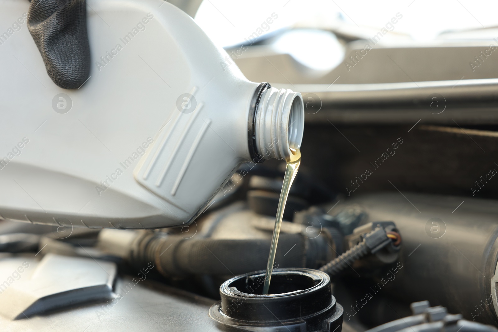 Photo of Man pouring motor oil into car engine, closeup