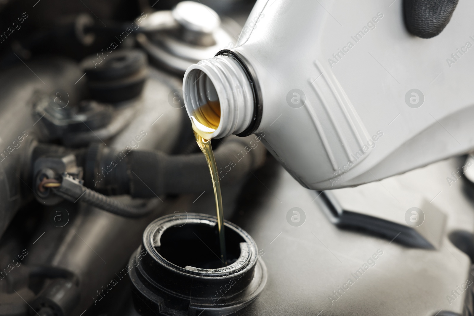 Photo of Pouring motor oil into car engine, closeup