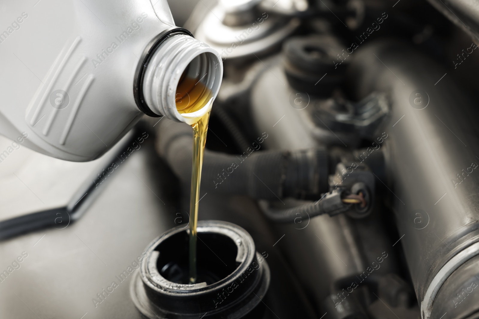 Photo of Pouring motor oil into car engine, closeup