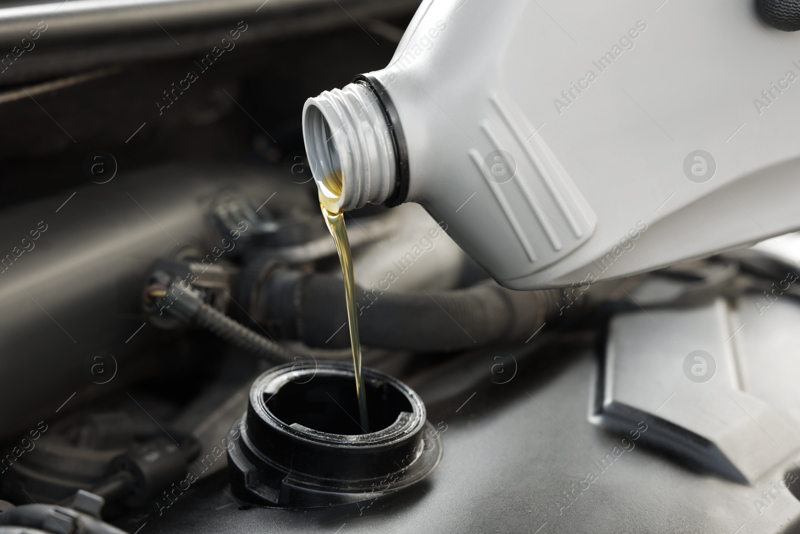 Photo of Pouring motor oil into car engine, closeup