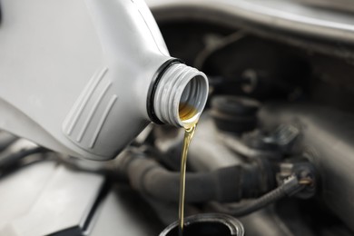 Photo of Pouring motor oil into car engine, closeup