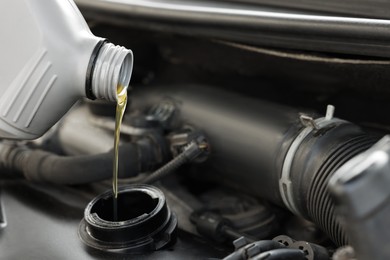 Photo of Pouring motor oil into car engine, closeup