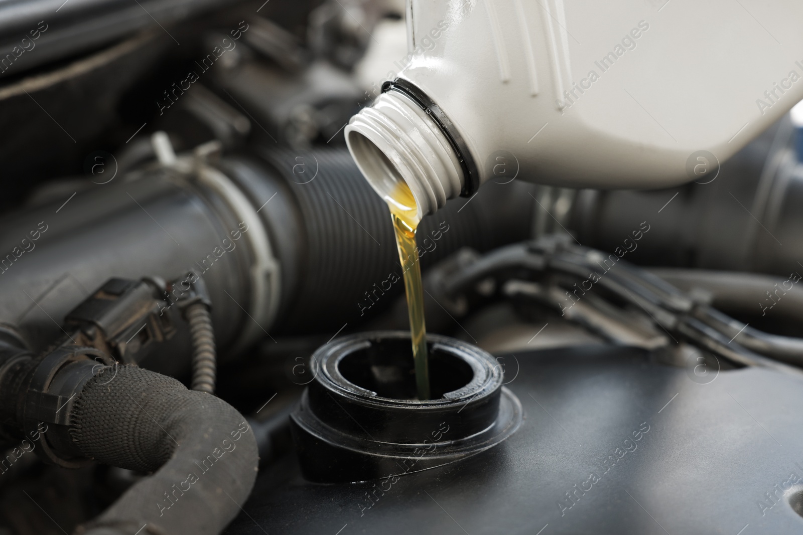 Photo of Pouring motor oil into car engine, closeup