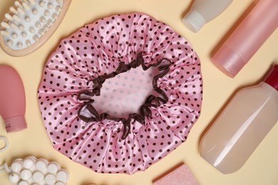 Photo of Shower cap and bath accessories on beige background, flat lay