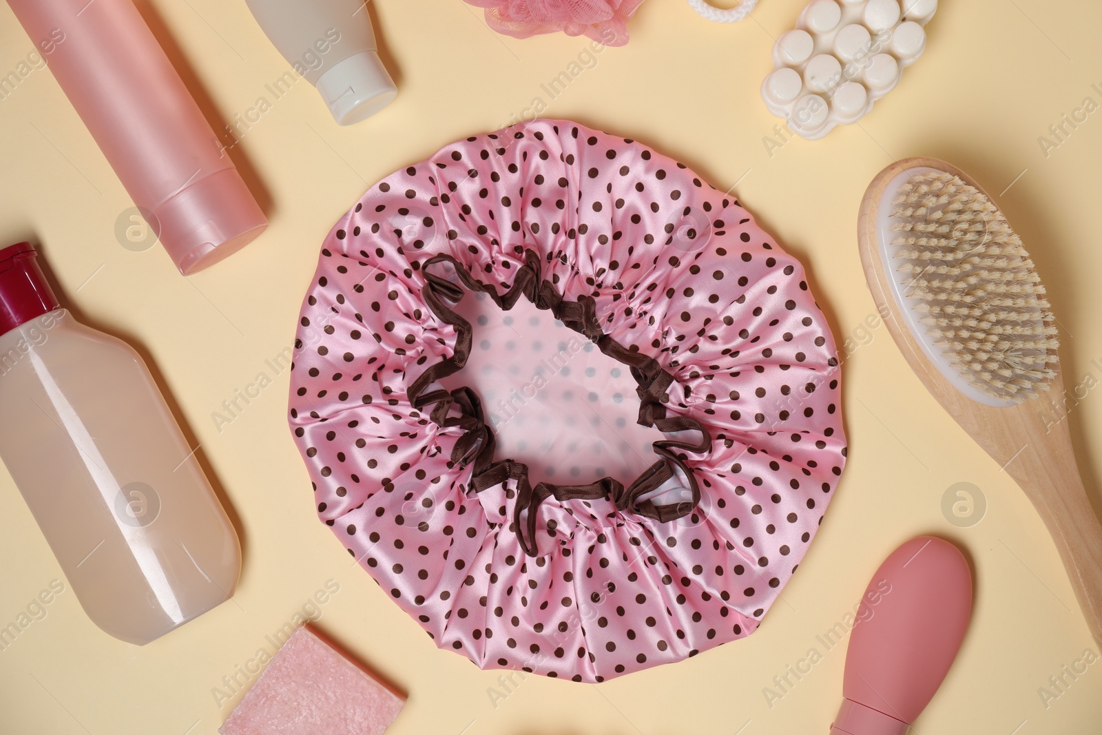 Photo of Shower cap and bath accessories on beige background, flat lay