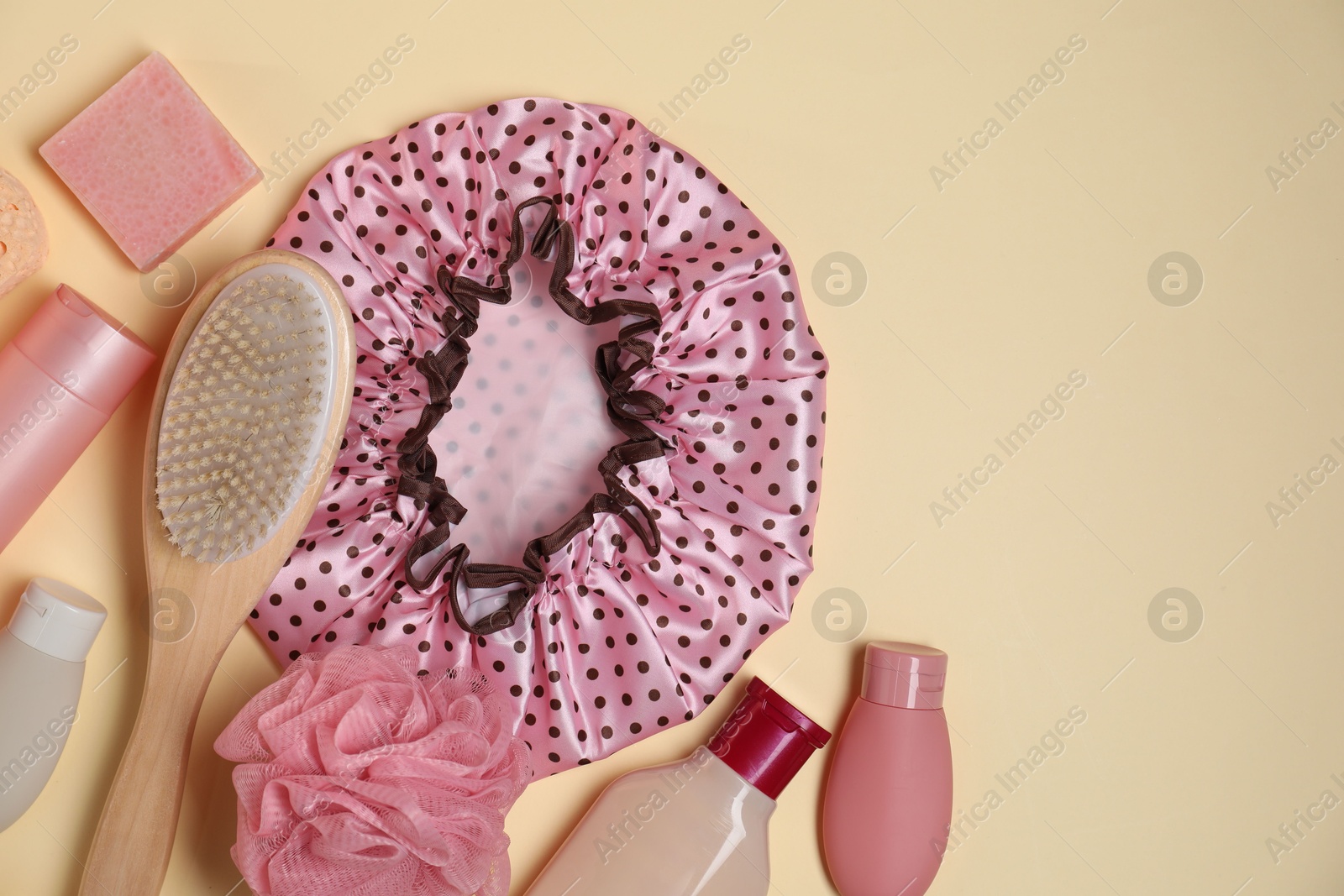 Photo of Shower cap and bath accessories on beige background, flat lay. Space for text