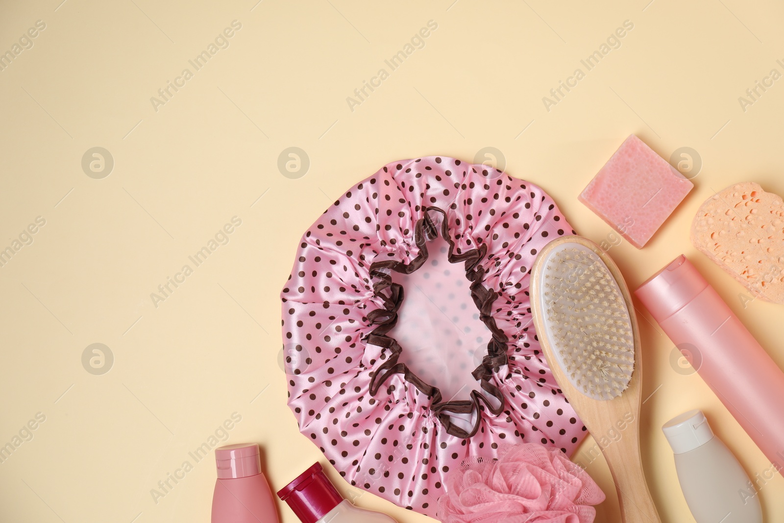 Photo of Shower cap and bath accessories on beige background, flat lay. Space for text