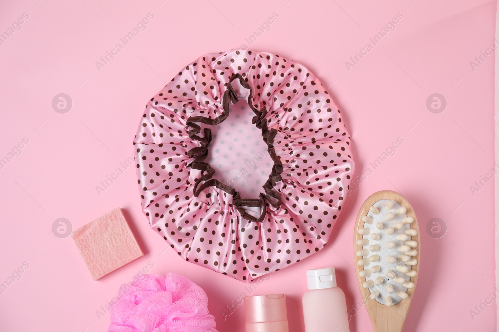 Photo of Shower cap and bath accessories on pink background, flat lay