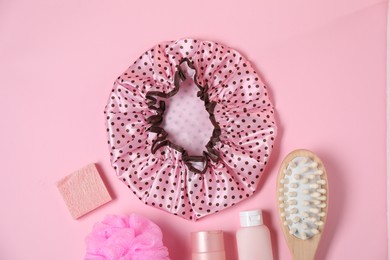 Photo of Shower cap and bath accessories on pink background, flat lay