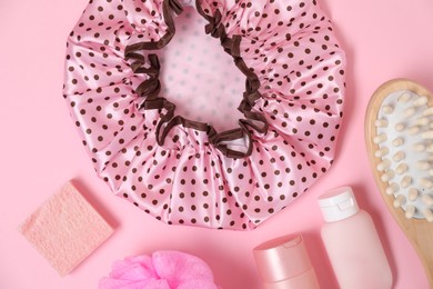 Photo of Shower cap and bath accessories on pink background, flat lay