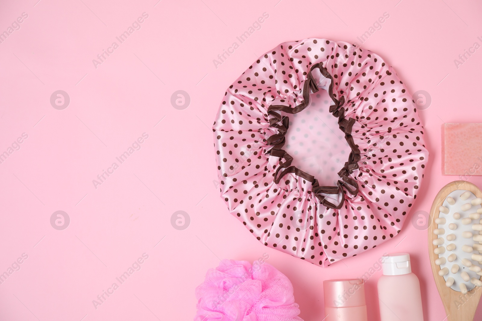 Photo of Shower cap and bath accessories on pink background, flat lay. Space for text