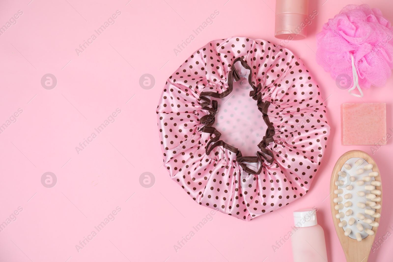 Photo of Shower cap and bath accessories on pink background, flat lay. Space for text