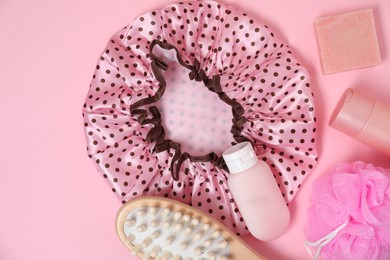 Photo of Shower cap and bath accessories on pink background, flat lay