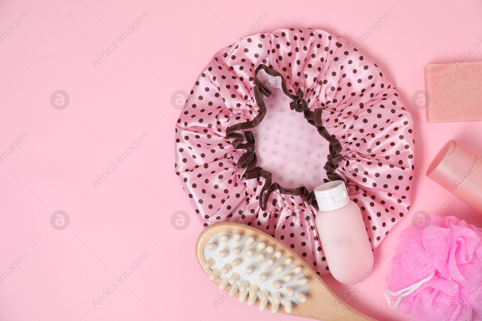 Photo of Shower cap and bath accessories on pink background, flat lay. Space for text