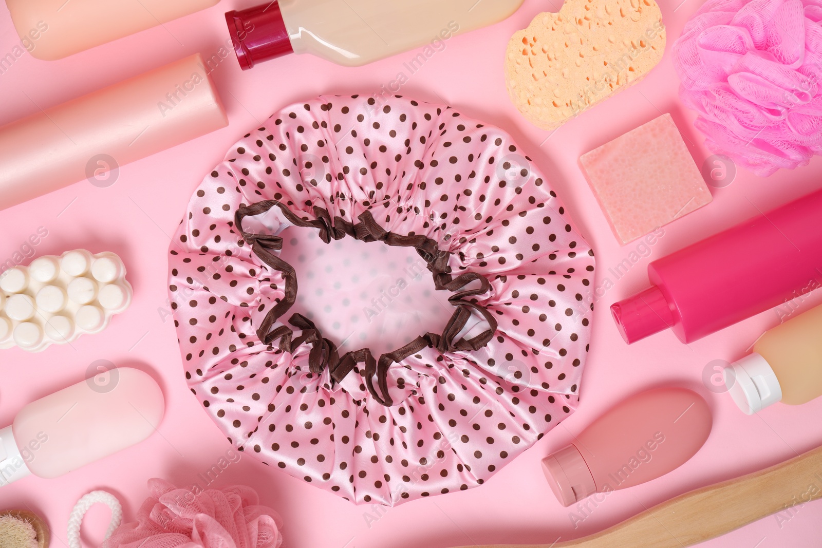 Photo of Shower cap and bath accessories on pink background, flat lay