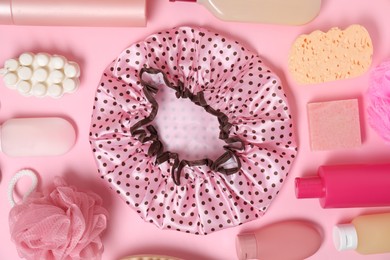 Photo of Shower cap and bath accessories on pink background, flat lay